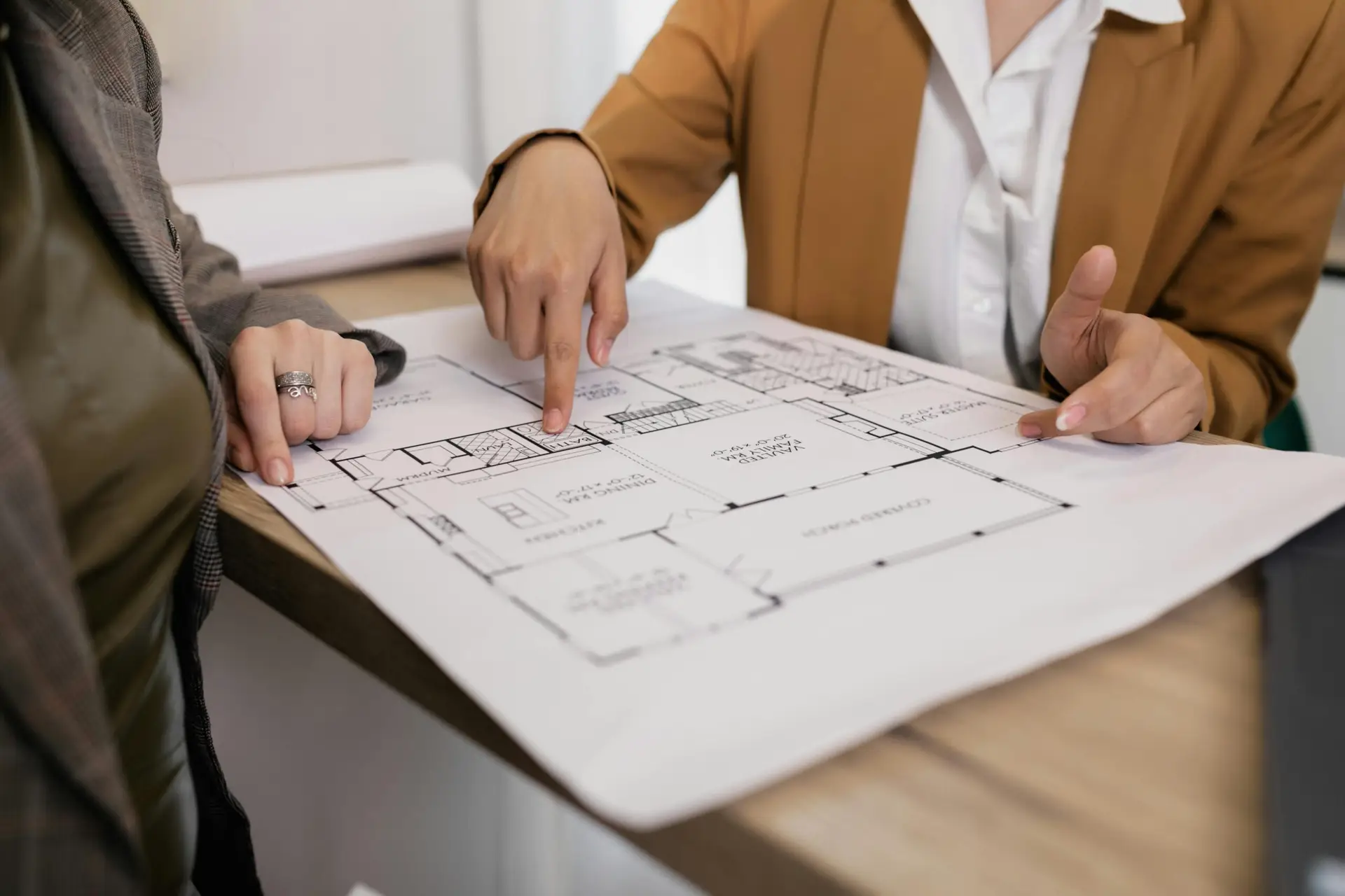 Two professionals reviewing architectural plans, focused on floor layout and design details.