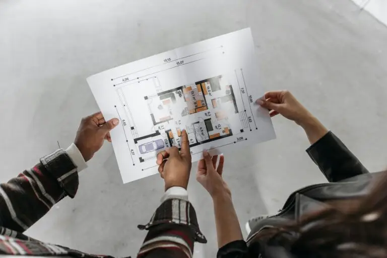 Two people reviewing architectural plans and measuring a new home design.